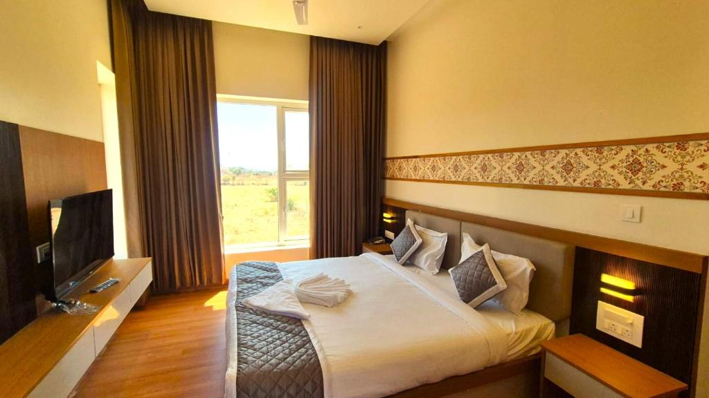 a hotel room with a bed and a television at Antilia Inn in Badami