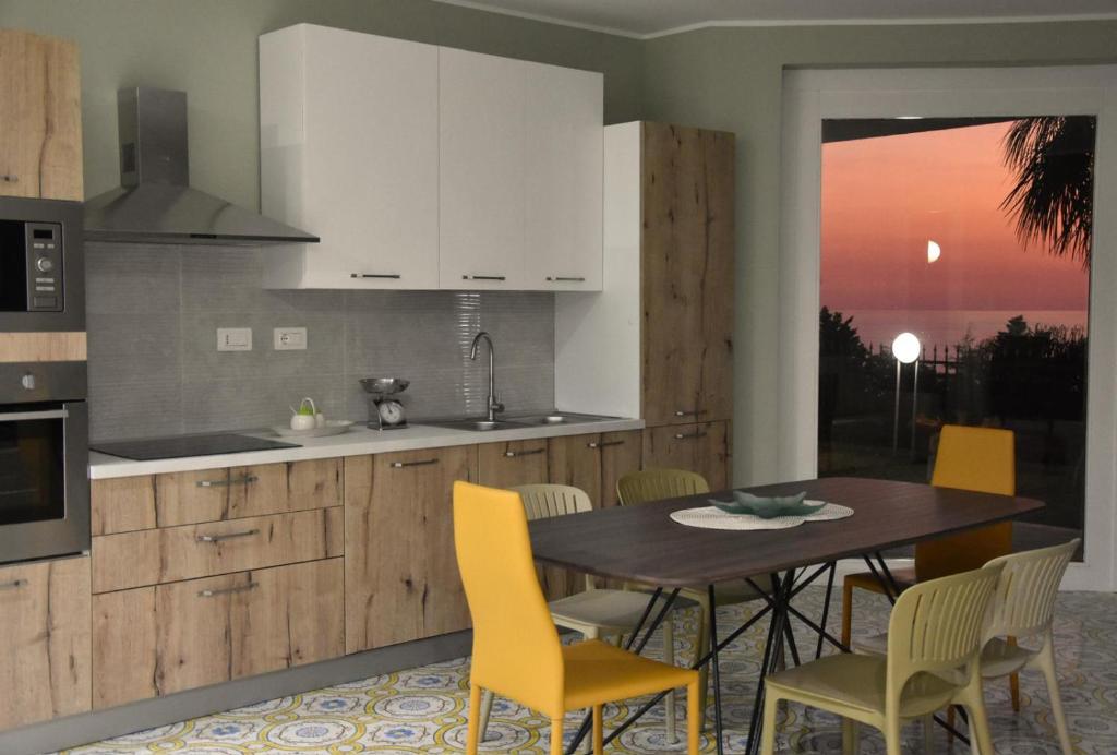 a kitchen with a wooden table and yellow chairs at Thalore room e apartments in Amantea