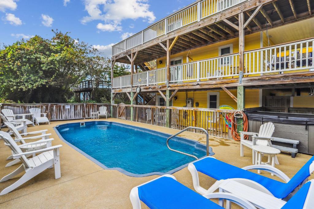 a swimming pool with chairs and a building at 3675 - Seaducktion in Duck