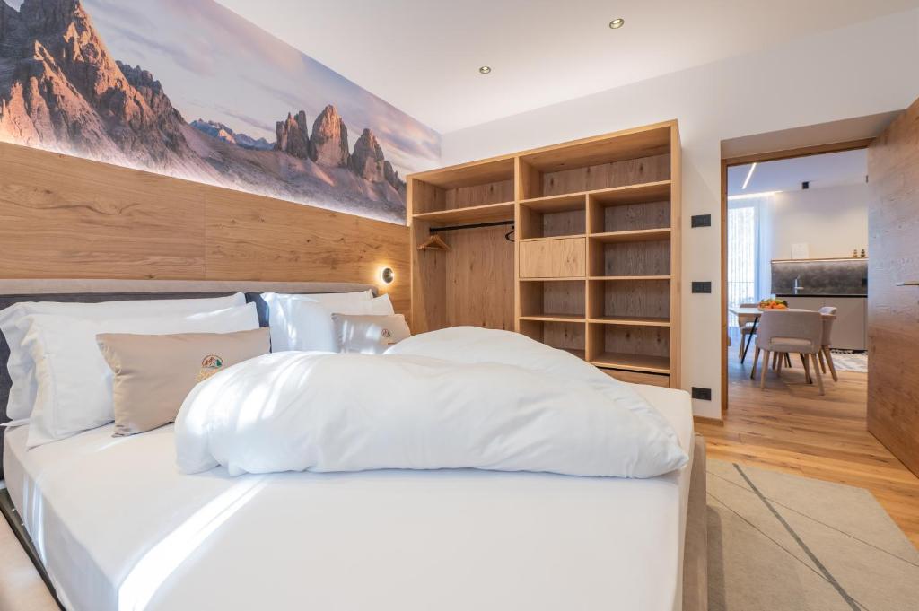 a bedroom with a large white bed and a dining room at Apartament Tre Cime in San Sigismondo