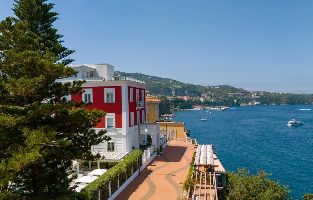 a red and white building next to a body of water at Hotel Villa Garden in Sant'Agnello
