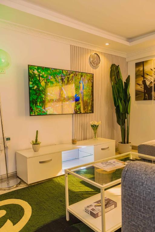 a living room with a table and a tv on the wall at Chic Modern Studio Apartment with Pool in Nanyuki