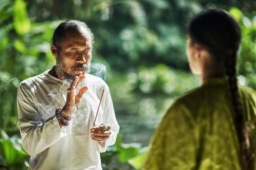 a man smoking a cigarette next to a woman at Four Seasons Resort Bali at Sayan in Ubud