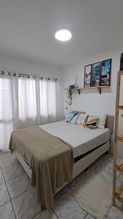 a bedroom with a large bed with white curtains at Casa Vila Mar Guesthouse in Guaratuba