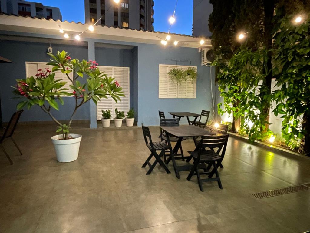 eine Terrasse mit Tischen, Stühlen und Topfpflanzen in der Unterkunft Flow Pousada in Maringá