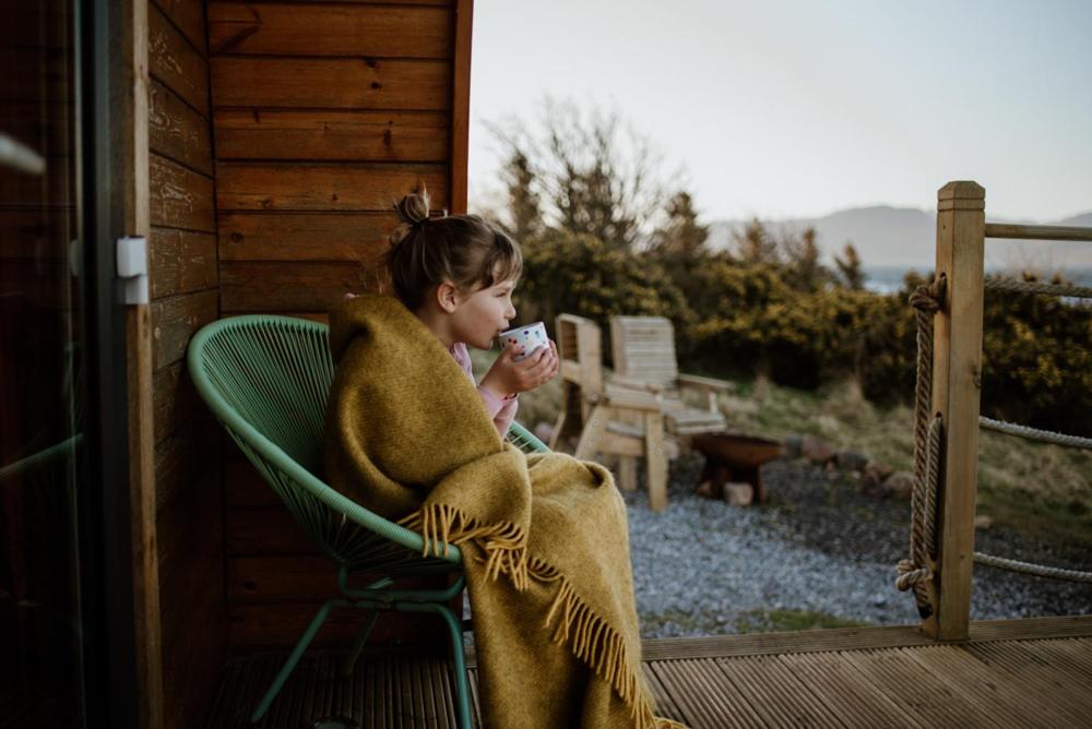 a little girl sitting in a chair on a porch at The Sleepy Crofter Glamping - Achiltibuie in Achiltibuie