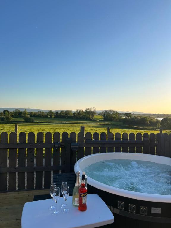 a hot tub on a deck with glasses of wine at Erne View Lodge in Lisnaskea