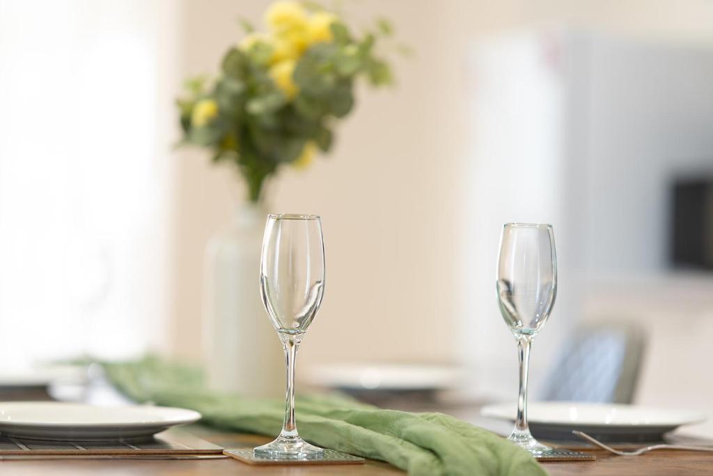 two wine glasses on a table with a vase at Vantage Stays in Gloucester