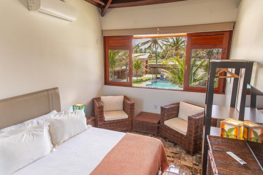 a bedroom with a bed and chairs and a pool at Beachfront Studio with Pool Caponga in Cascavel
