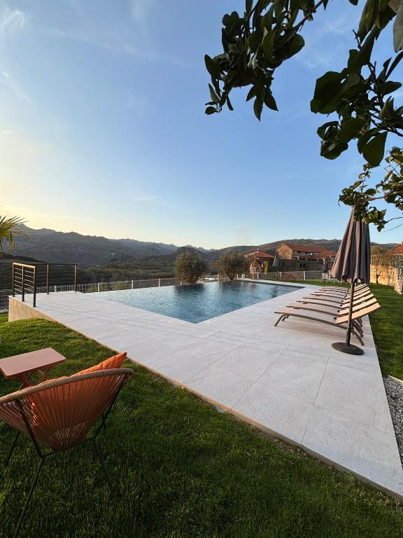 a swimming pool with two lawn chairs and an umbrella at Estrela do Gerês - Casa Fernandes in Outeiro