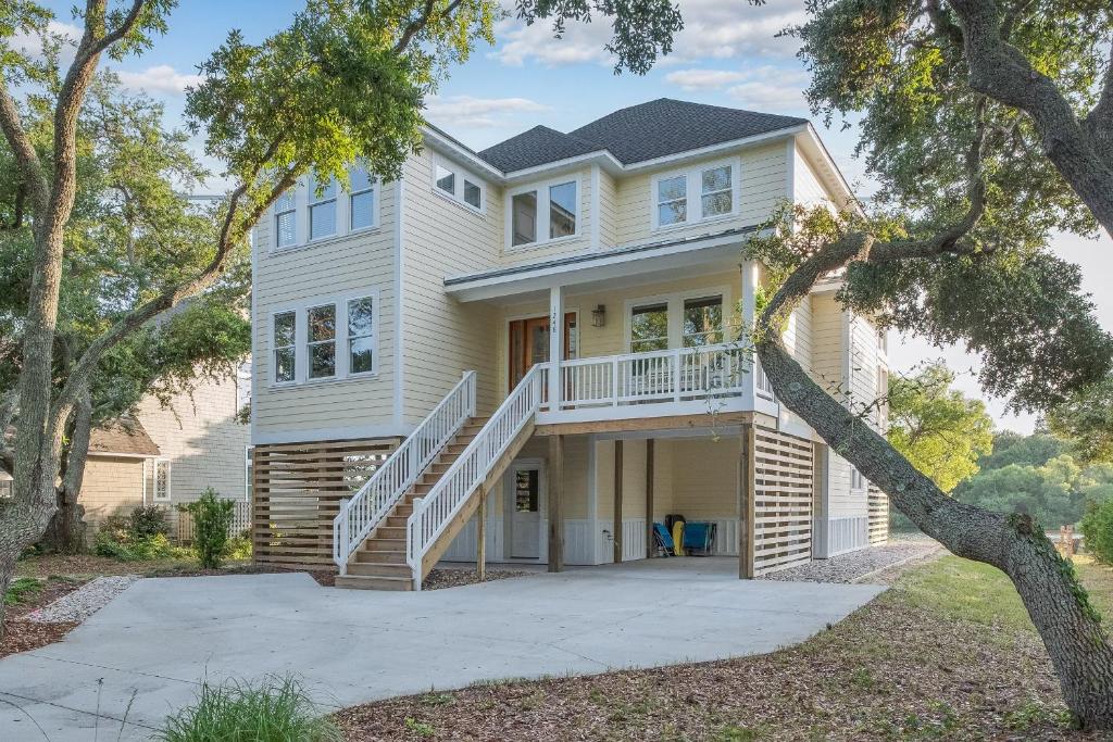 a large white house with a porch and stairs at 1064 - Sunset Cottage in Corolla