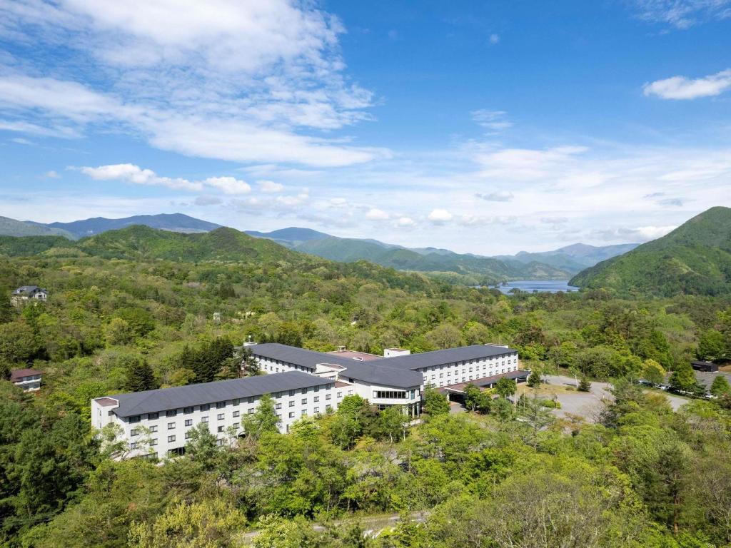 an overhead view of a building with mountains in the background at Mercure Urabandai Resort & Spa in Kitashiobara