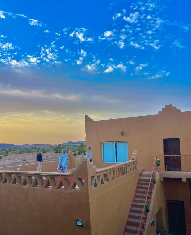 two people standing on the balcony of a house at Dar Talmoudi ,Traditional Riad, Local Food, Camel , Desert Excursions in Tagounite