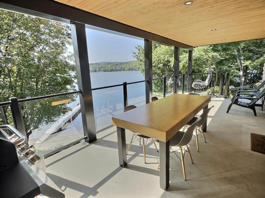 a table and chairs on a balcony with a view of the water at Sir'Eau d'Érable in St-Ferdinand
