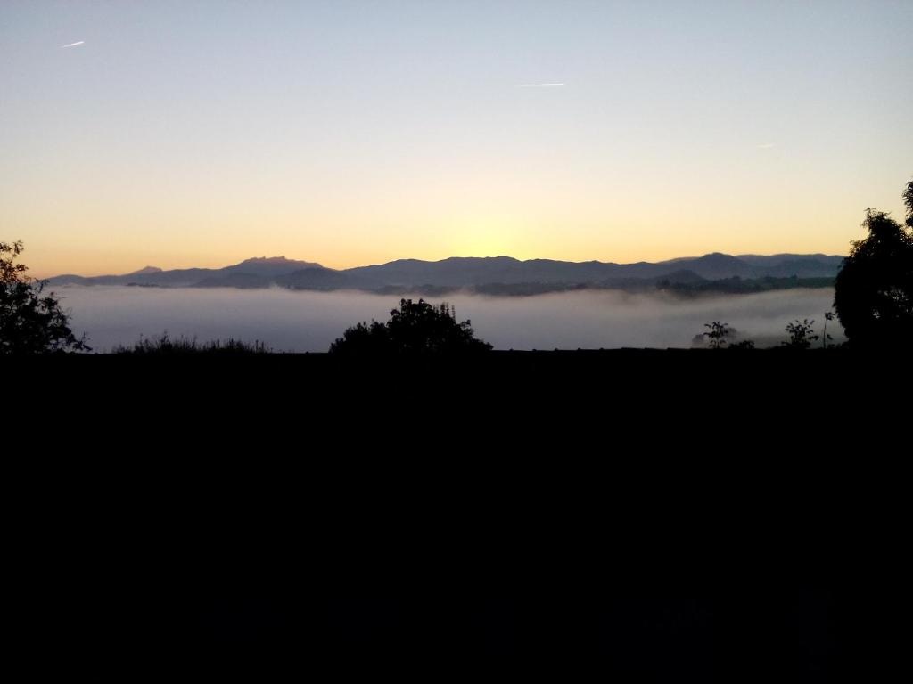 a view of a foggy field with the sunset in the background at Casa Rural Aristondo Agroturismo in San Sebastián