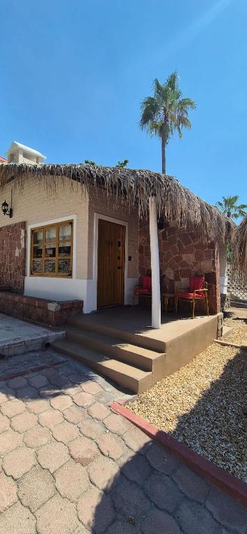 a house with a thatched roof with a palm tree at Sandy Shores Cabaña 10A in La Paz