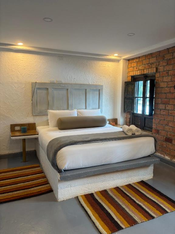 a bedroom with a large bed with a brick wall at Kaza Living Usaquén in Bogotá