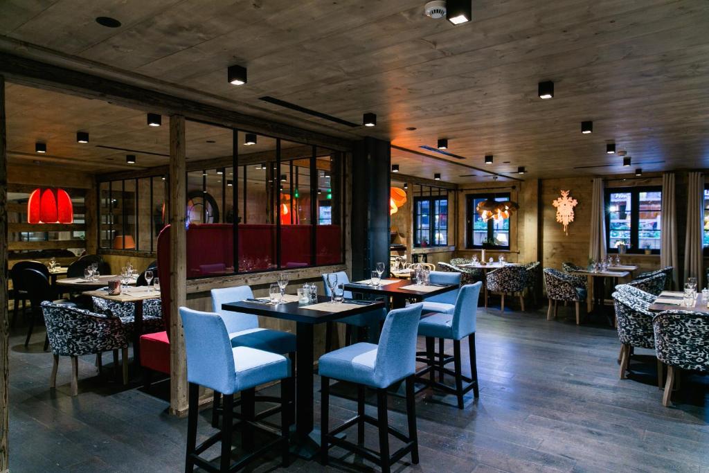 a dining room with tables and chairs in a restaurant at Chalet-Hôtel La Marmotte, La Tapiaz & SPA, The Originals Relais in Les Gets