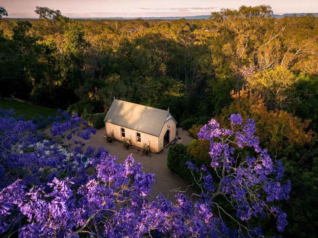 an old house in the middle of a garden with purple flowers at Stone Guest House Ebenezer in Ebenezer