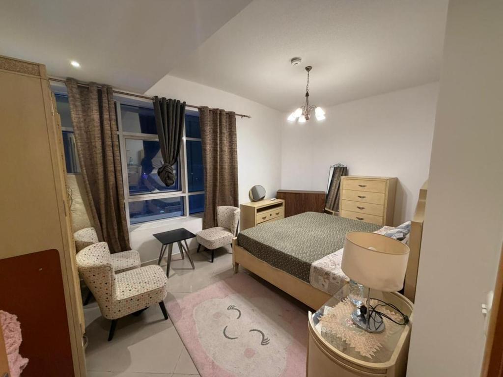 a bedroom with a bed and a chair and a window at A luxurious room with a breathtaking view in Sharjah
