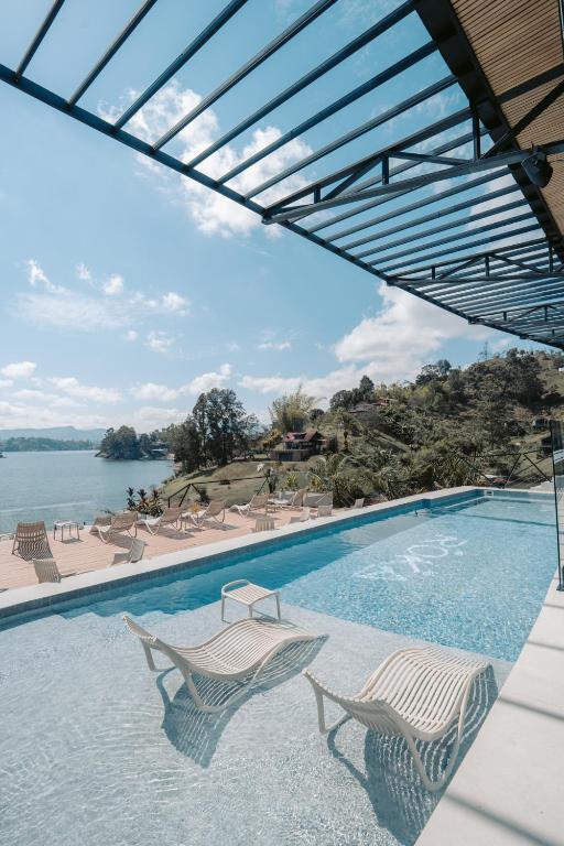 a swimming pool with two chairs and the water at Roka Hotel in Guatapé