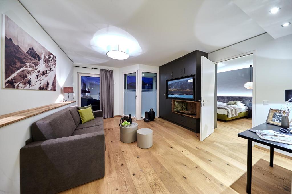 a living room with a couch and a tv at TWO TIMEZ - Boutique Hotel in Zell am See