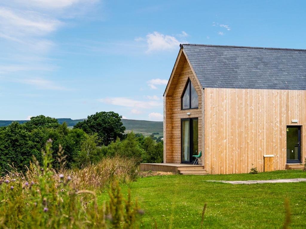 a wooden house on a grassy field with trees at Mars 4 - Uk50474 in Greenhaugh