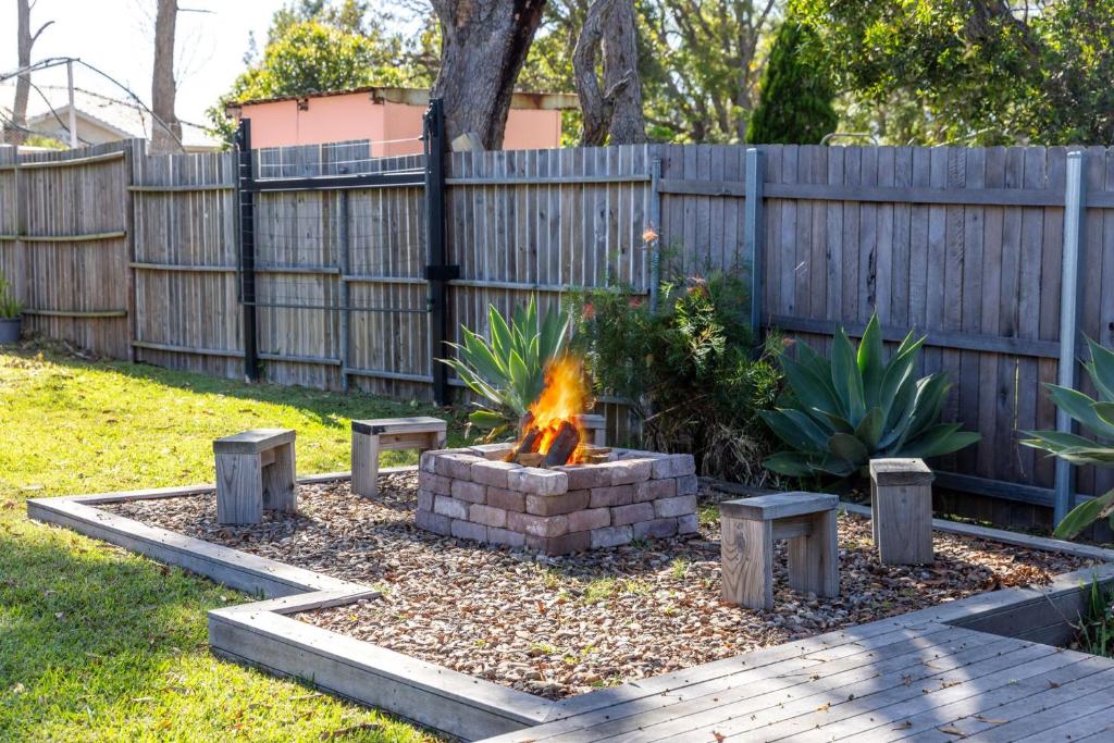 a fire pit in a backyard with a fence at Beauts - Pet Friendly - 5 Mins Walk to Beach in Culburra Beach