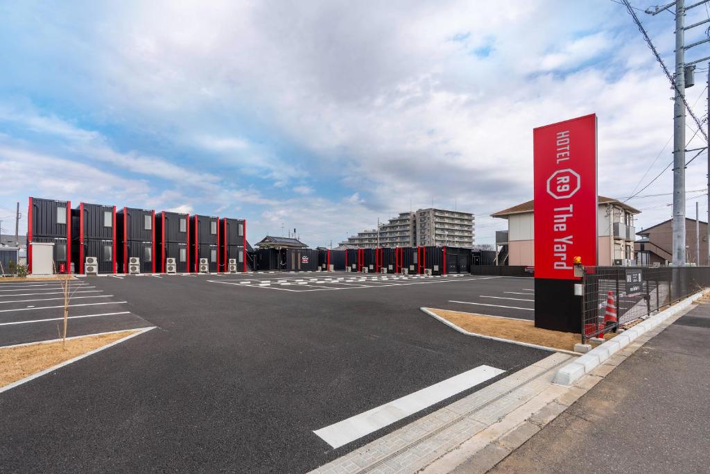 an empty parking lot with a red sign in the middle at HOTEL R9 The Yard Ushiku in Ushiku
