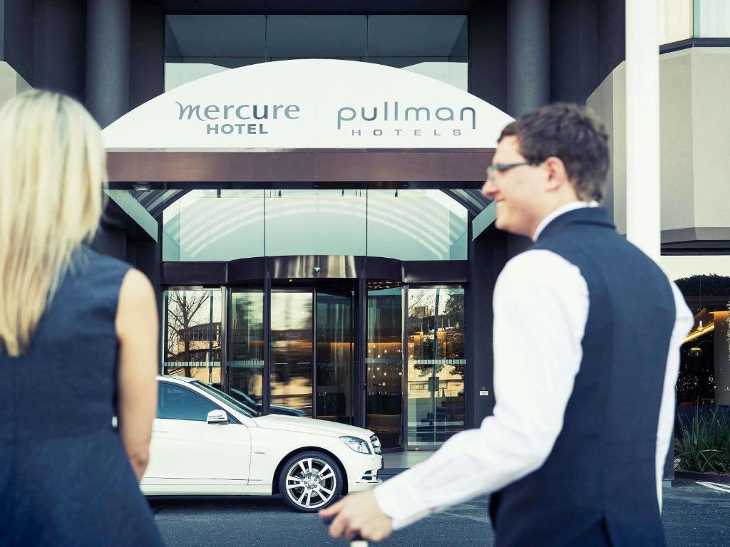 a man and a woman walking in front of a car at Mercure Melbourne Albert Park in Melbourne