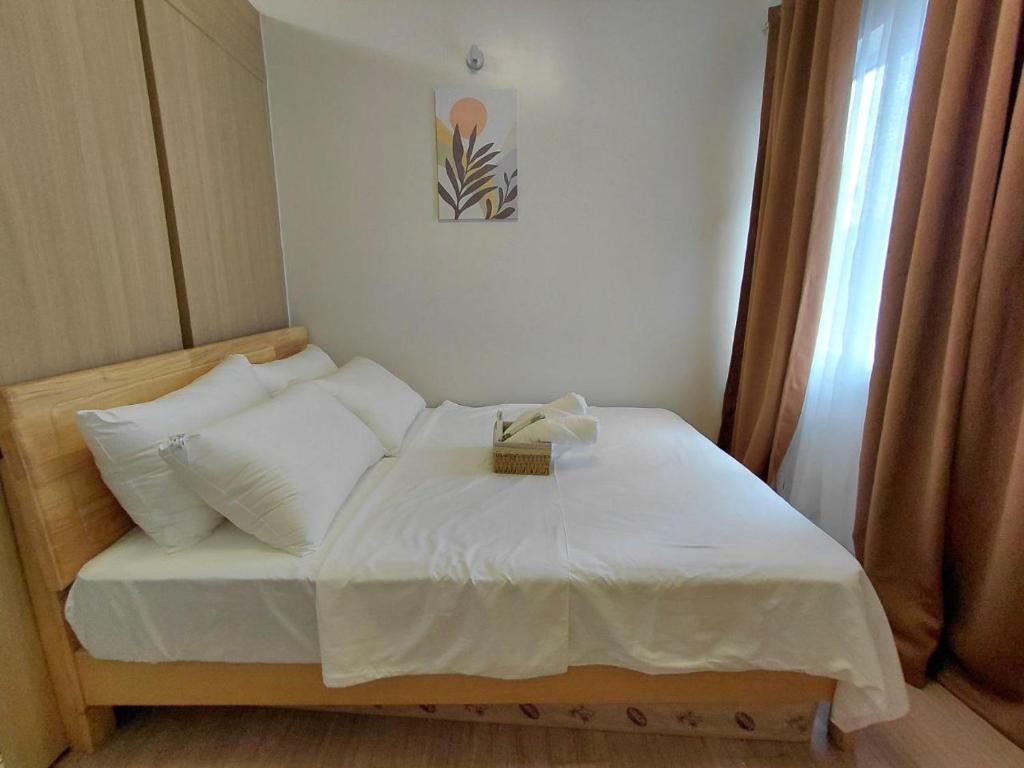 a bed with white sheets and pillows in a room at SMDC Trees Residences Jim's Staycation in Manila