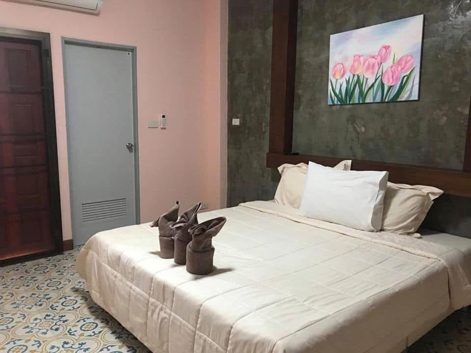 a bedroom with a large white bed with shoes on it at Satakanta Resort Lampang in Ban Nong Chaeng