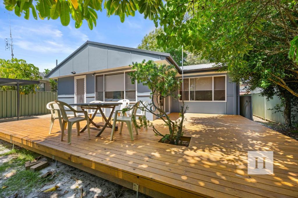a wooden deck with a table and chairs on it at Garden Cottage Noraville in Toukley