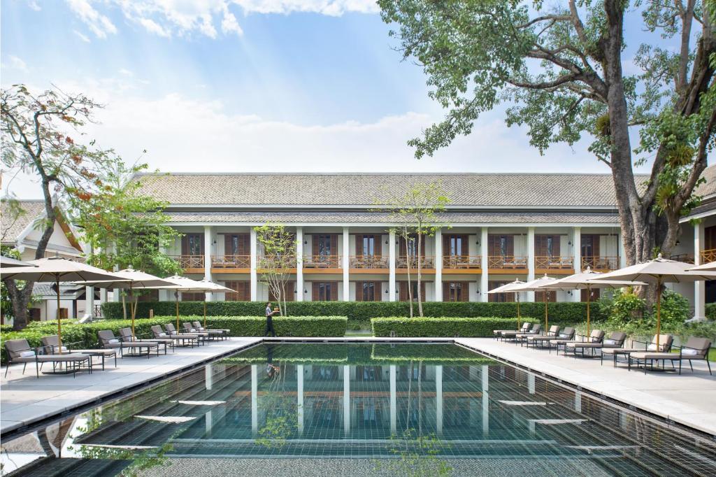 an exterior view of a resort with a pool and chairs at Avani+ Luang Prabang Hotel in Luang Prabang