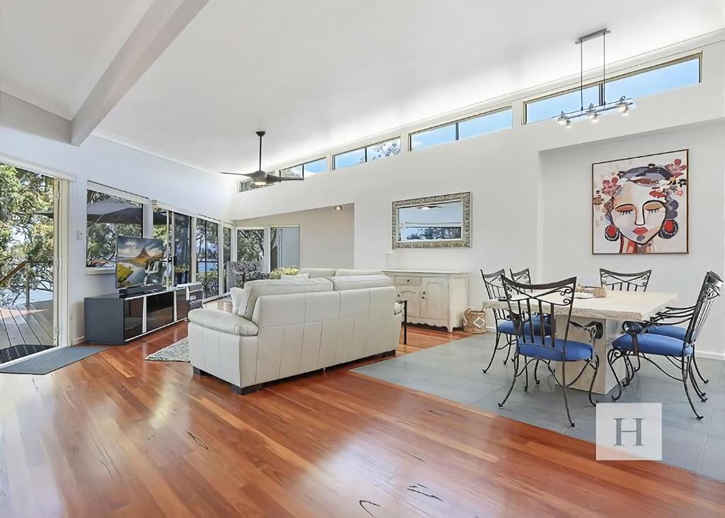 a living room with a white couch and a table at Karinyah in Summerland Point