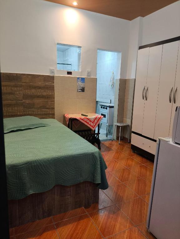 a bedroom with a bed and a table and a kitchen at Microcasa Caledônia Nova Friburgo in Nova Friburgo