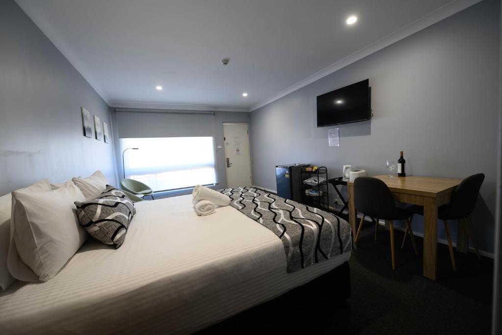 a bedroom with a bed and a table and a desk at Old Maitland Inn - Rutherford in Maitland