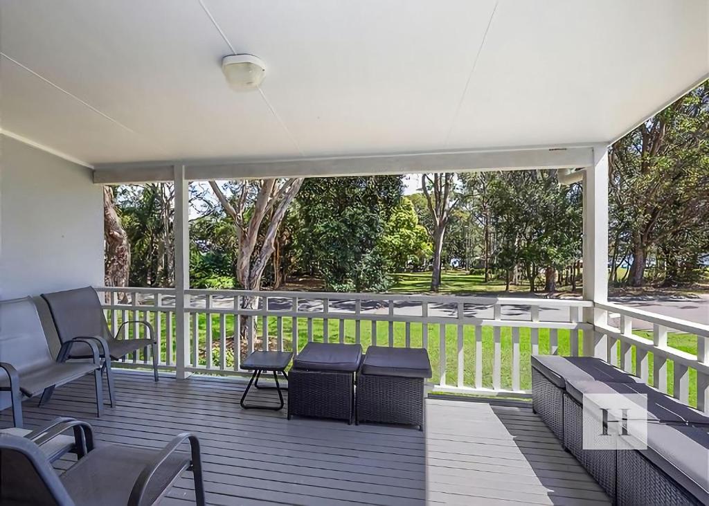 a deck with benches and chairs on a porch at Lakeshores Villa in Cams Wharf