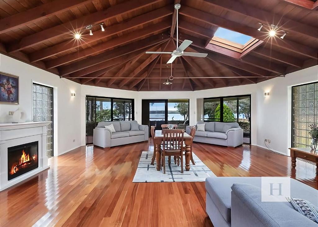 a living room with a ceiling fan and a fireplace at Mannering Lake House in Mannering Park