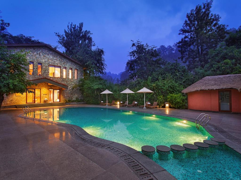 a swimming pool in front of a house at Taj Corbett Resort and Spa Uttarakhand in Rāmnagar