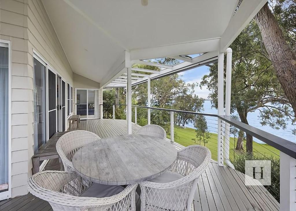 a patio with a table and chairs on a porch at Relaxing Getaway in Summerland Point