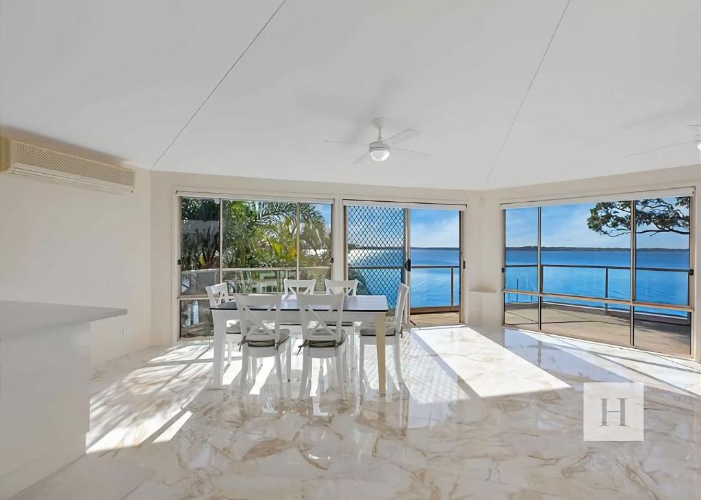 a dining room with a table and views of the ocean at Sunset Lakehouse in Toukley