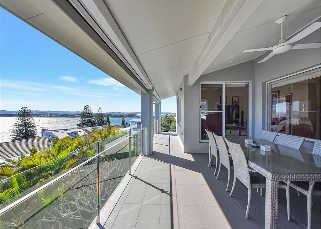 a balcony with a dining table and a view of the water at The Sea Serenade in Blacksmiths