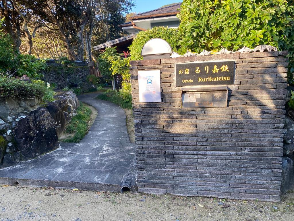 a sign on a brick wall next to a path at お宿るり嘉鉄 in Setouchi