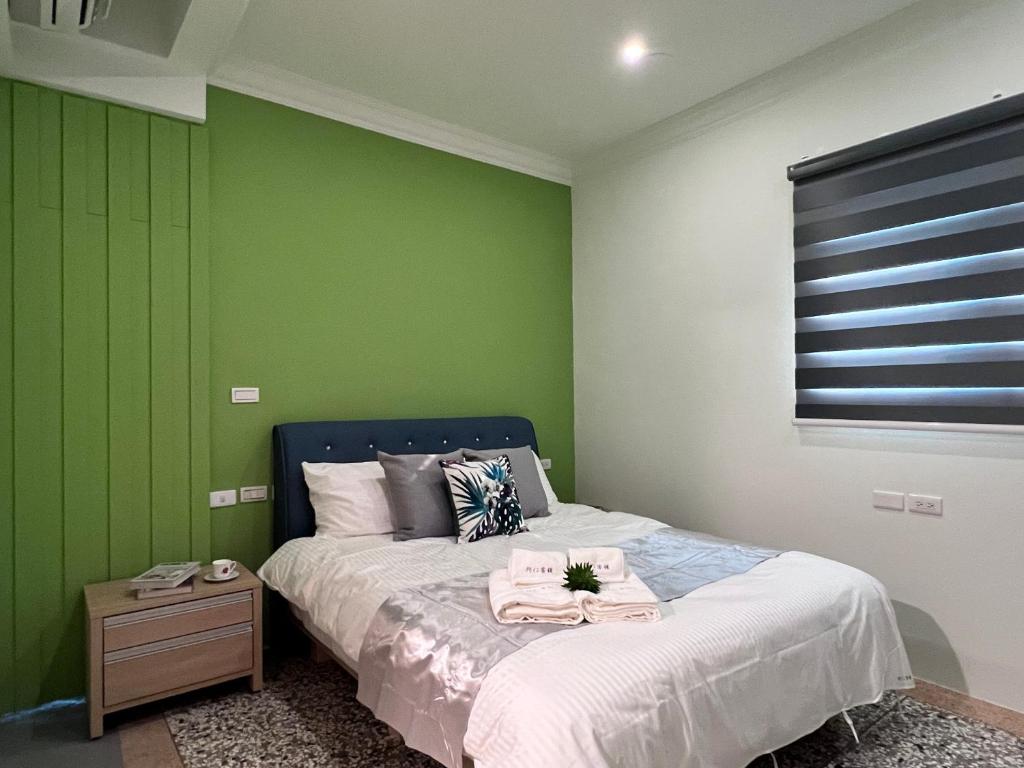 a bedroom with a bed and a green wall at Aren Inn in Zhushan