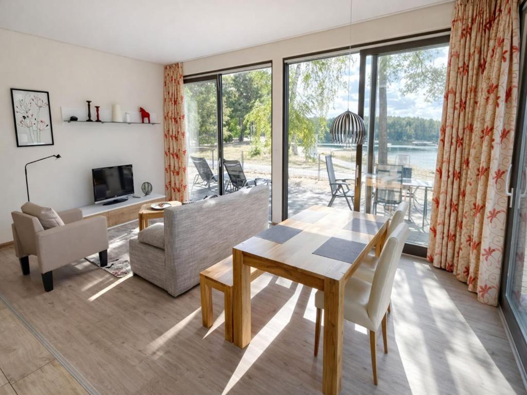 a living room with a table and chairs and a large window at Bernsteinsee Homes and Ferien Beach House 2 in Sassenburg
