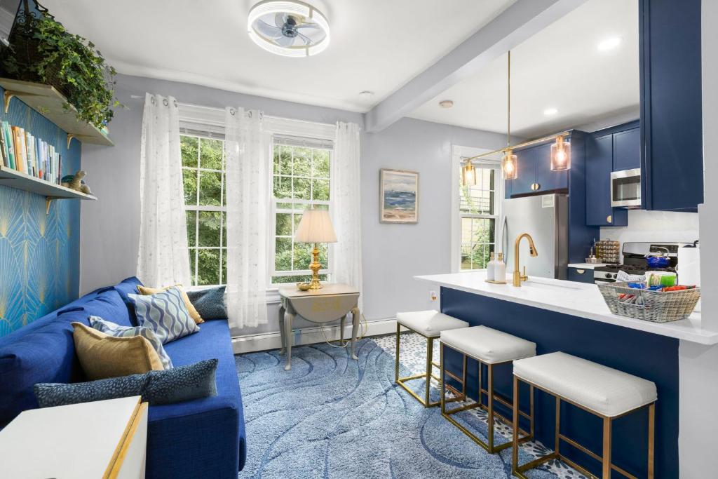 a blue living room with a blue couch and a kitchen at Bright 2BR Retreat Walk to PATH NYC Access in Jersey City