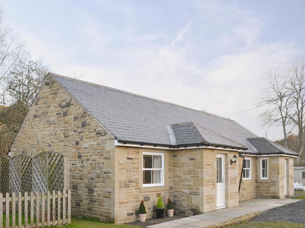 a small stone house with a black roof at Railway Cuttings in Falstone