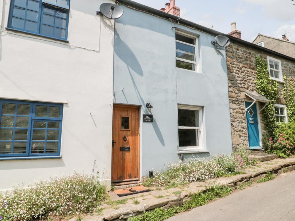 a white house with blue windows and a wooden door at Lea Cottage in Bridport