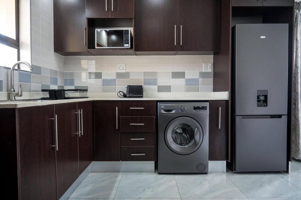 a kitchen with a refrigerator and a washing machine at Little leisures in Matsapha